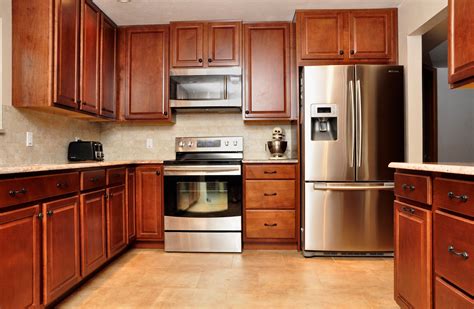 stainless steel appliances with wood cabinets|kitchen with dark wood cabinet.